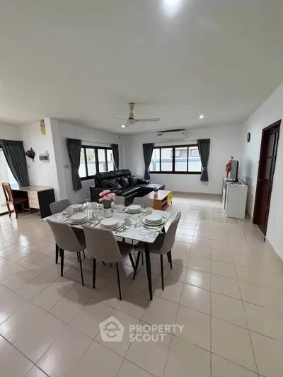 Spacious living room with dining area, modern furniture, and large windows for natural light.