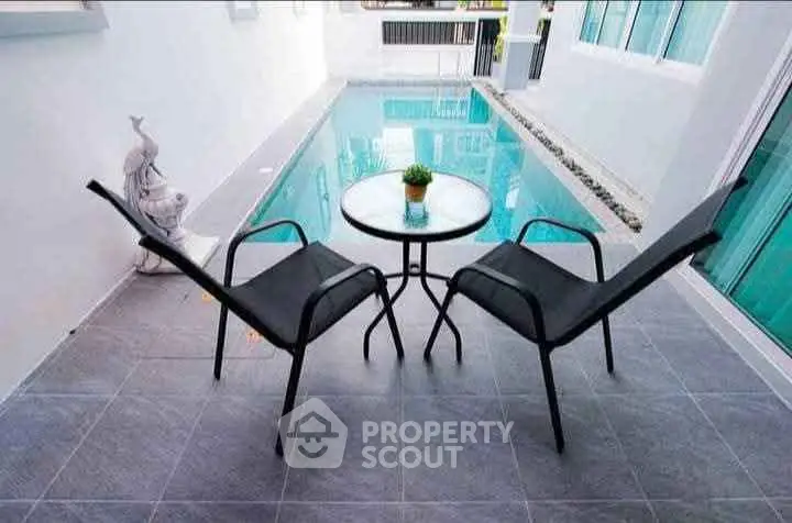 Chic poolside patio with modern chairs and table, perfect for relaxation and entertaining.