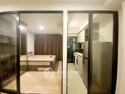Modern apartment interior with bedroom and kitchen featuring sleek design and glass partitions.