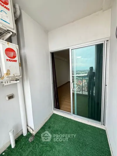 Cozy balcony with artificial grass and sliding glass door, offering a glimpse of a scenic view.