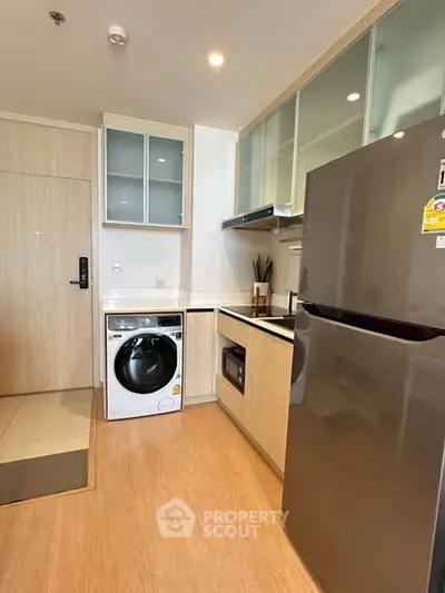 Modern kitchen with sleek appliances and washing machine in compact layout