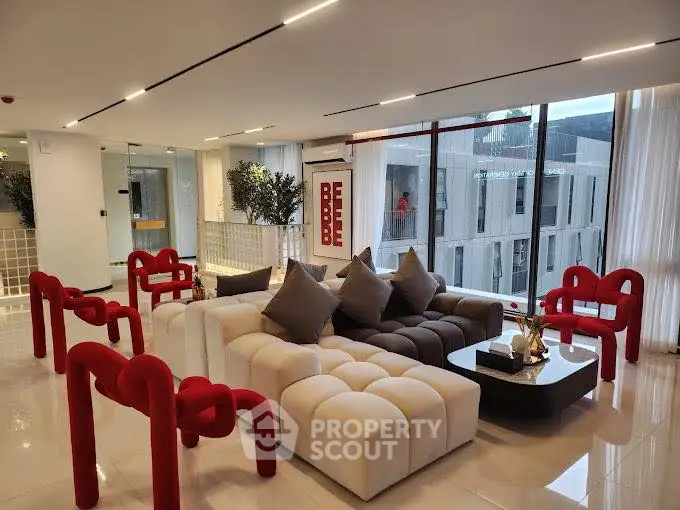 Luxurious modern living room with stylish red and white furniture, large windows, and elegant decor.