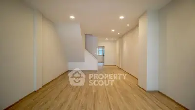 Spacious empty room with wooden flooring and recessed lighting, ideal for customization.