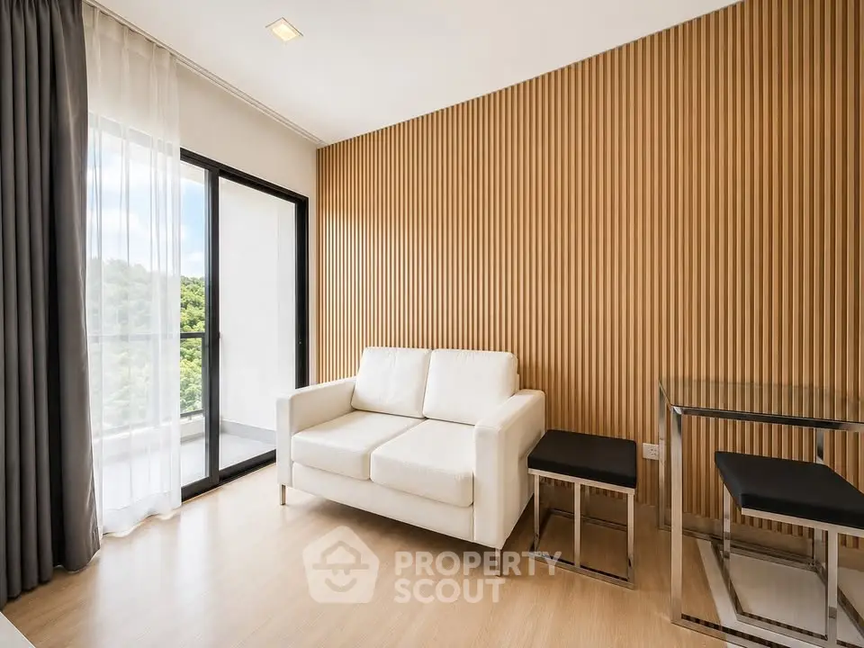 Modern living room with white sofa and glass table, featuring wooden accent wall and balcony view.