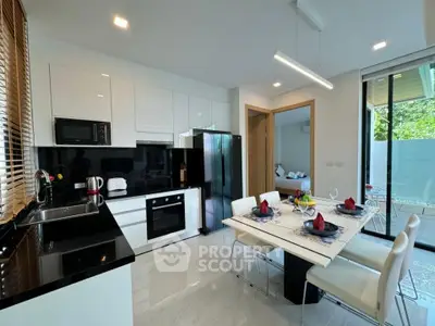 Modern kitchen with sleek black countertops and dining area in bright open layout