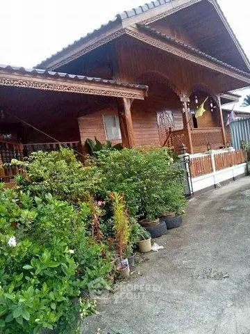 Charming traditional wooden house with lush garden and inviting porch.