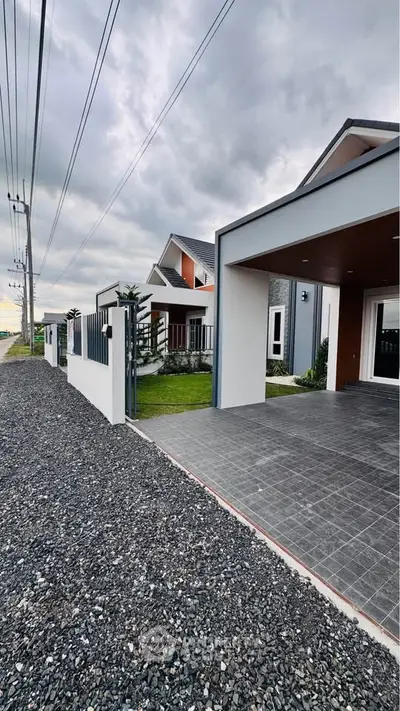 Modern suburban home with sleek driveway and landscaped garden under cloudy skies.