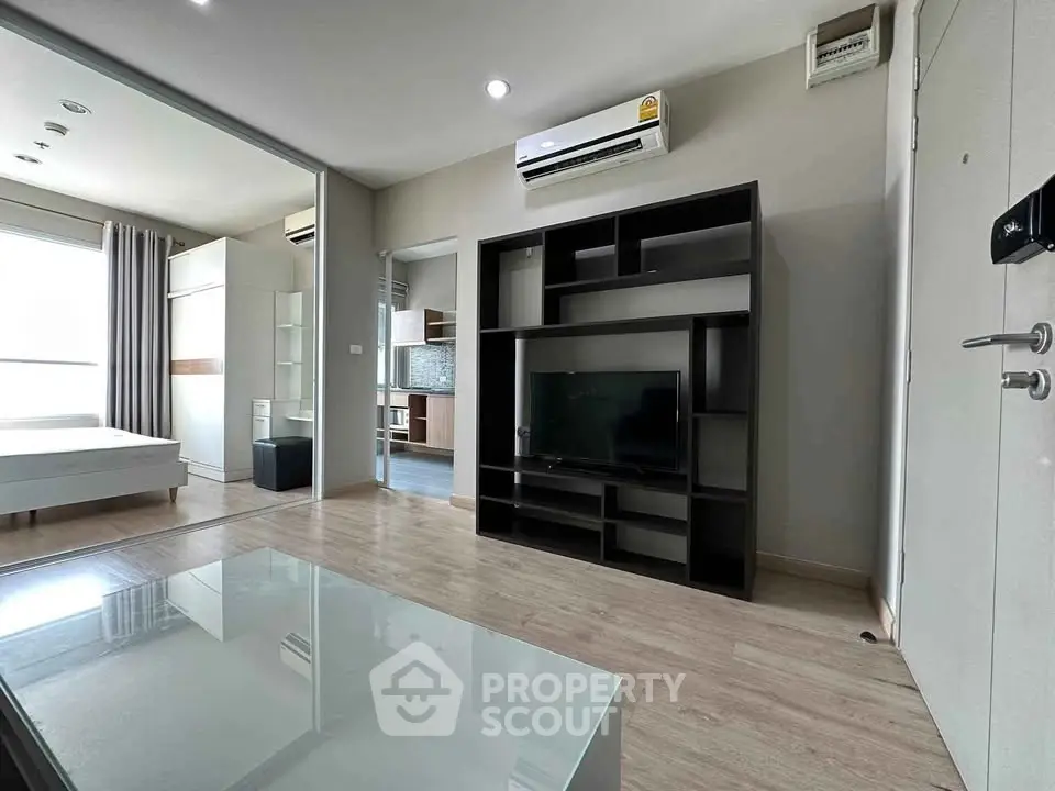 Modern apartment interior with sleek living room and adjacent bedroom, featuring stylish furniture and natural light.