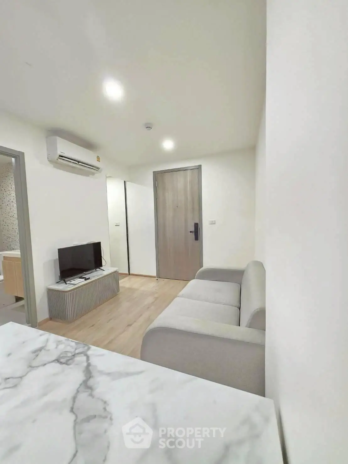 Modern living room with sleek design and neutral tones, featuring a cozy sofa and flat-screen TV.