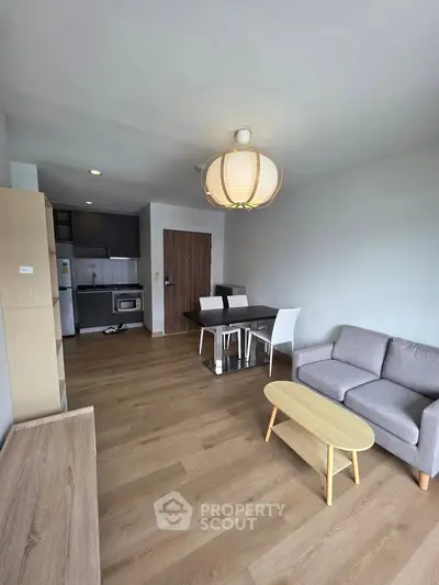 Modern living room with open kitchen, stylish furniture, and wooden flooring in a cozy apartment.
