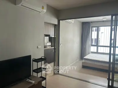 Modern apartment interior with sliding glass doors, featuring a cozy bedroom and compact living area.