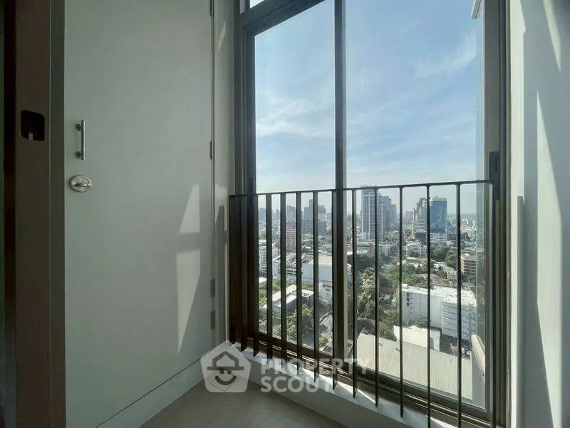 Stunning city view from high-rise apartment balcony with floor-to-ceiling windows.