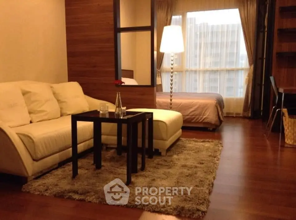 Cozy studio apartment with modern decor and large window for natural light.
