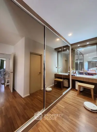 Spacious bedroom with mirrored closet doors and elegant wooden flooring