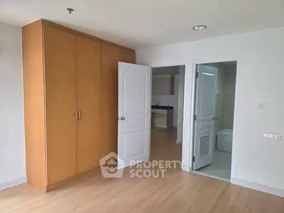 Spacious bedroom with wooden wardrobe and ensuite bathroom in modern apartment