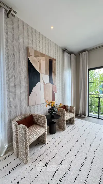 Stylish living room with modern art, elegant chairs, and large windows opening to a balcony view.