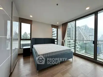 Spacious bedroom with large windows offering stunning city views in modern apartment.