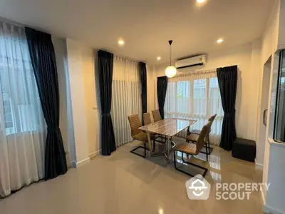 Modern dining area with elegant table and chairs, surrounded by large windows and stylish curtains.