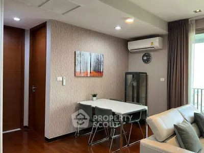 Modern living room with sleek furniture and air conditioning, featuring a stylish dining area and wall art.