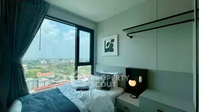 Modern bedroom with large window offering stunning city view, stylish decor, and cozy ambiance.