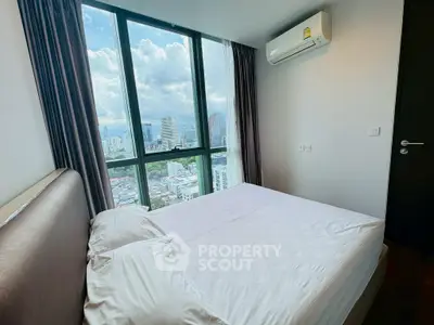 Modern bedroom with city view and large windows in a high-rise apartment.