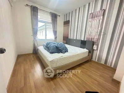 Cozy bedroom with wooden flooring and large window for natural light