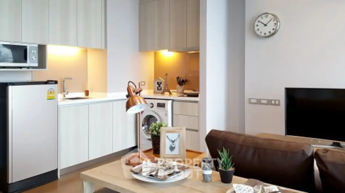 Modern open-plan living room with kitchen, featuring stylish decor and appliances.