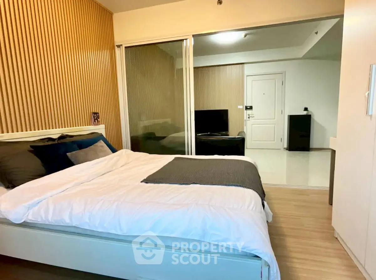Modern bedroom with stylish wood paneling and sliding glass doors in a contemporary apartment.
