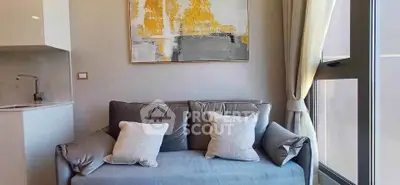 Modern living room with stylish sofa and abstract art, featuring natural light from large window.