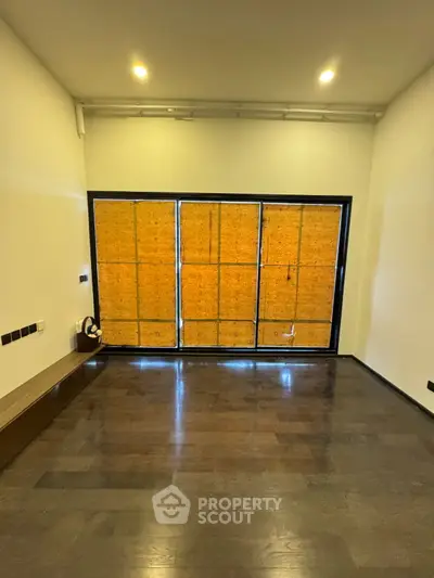 Spacious empty room with large windows and dark wooden flooring, ideal for customization.