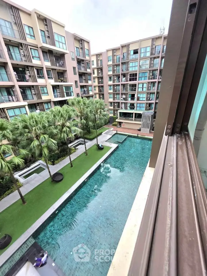 Modern apartment complex with pool and lush greenery view from balcony.
