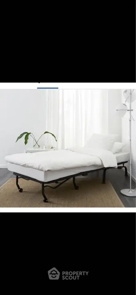 Modern minimalist bedroom with sleek bed frame and cozy white bedding, complemented by a stylish floor lamp.
