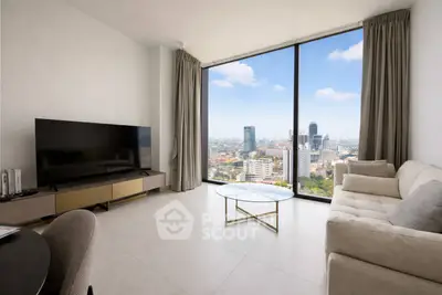 Modern living room with floor-to-ceiling windows offering stunning city views, elegant furnishings, and natural light.