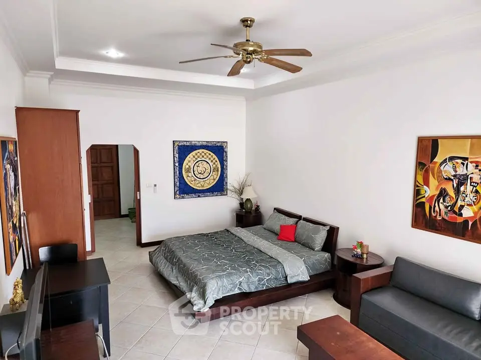 Spacious bedroom with modern decor and ceiling fan, perfect for comfort and relaxation.