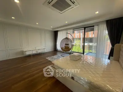 Spacious bedroom with modern decor and large windows overlooking greenery.