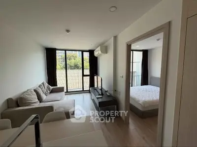 Modern apartment with cozy living room and bedroom, featuring large windows and stylish furnishings.