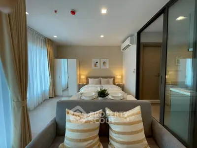 Modern bedroom with cozy decor and natural light, featuring a stylish sofa and elegant curtains.