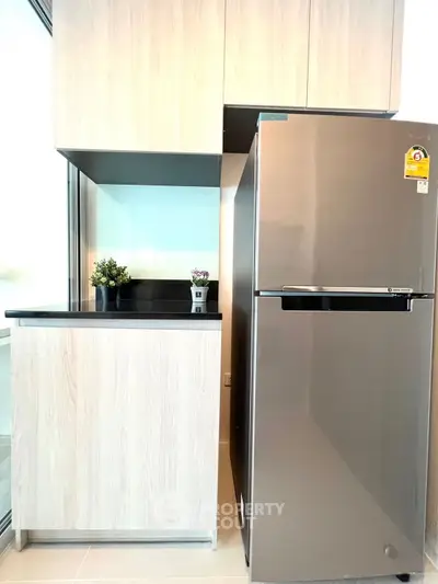 Modern kitchen with sleek stainless steel fridge and light wood cabinets