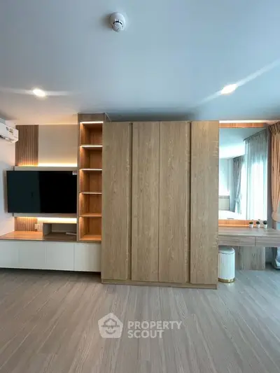 Modern living room with sleek wooden cabinetry and mounted TV, featuring elegant lighting and spacious design.