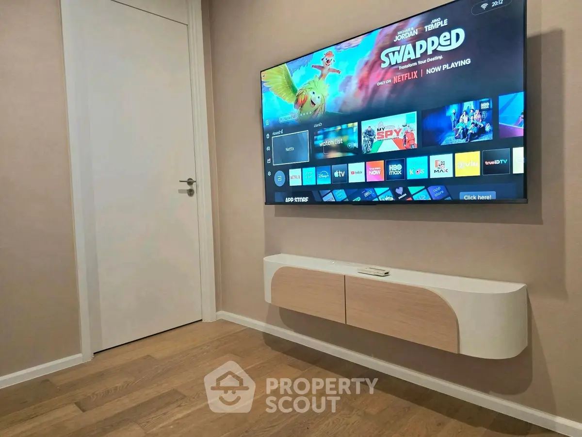Modern living room with wall-mounted TV and sleek wooden flooring