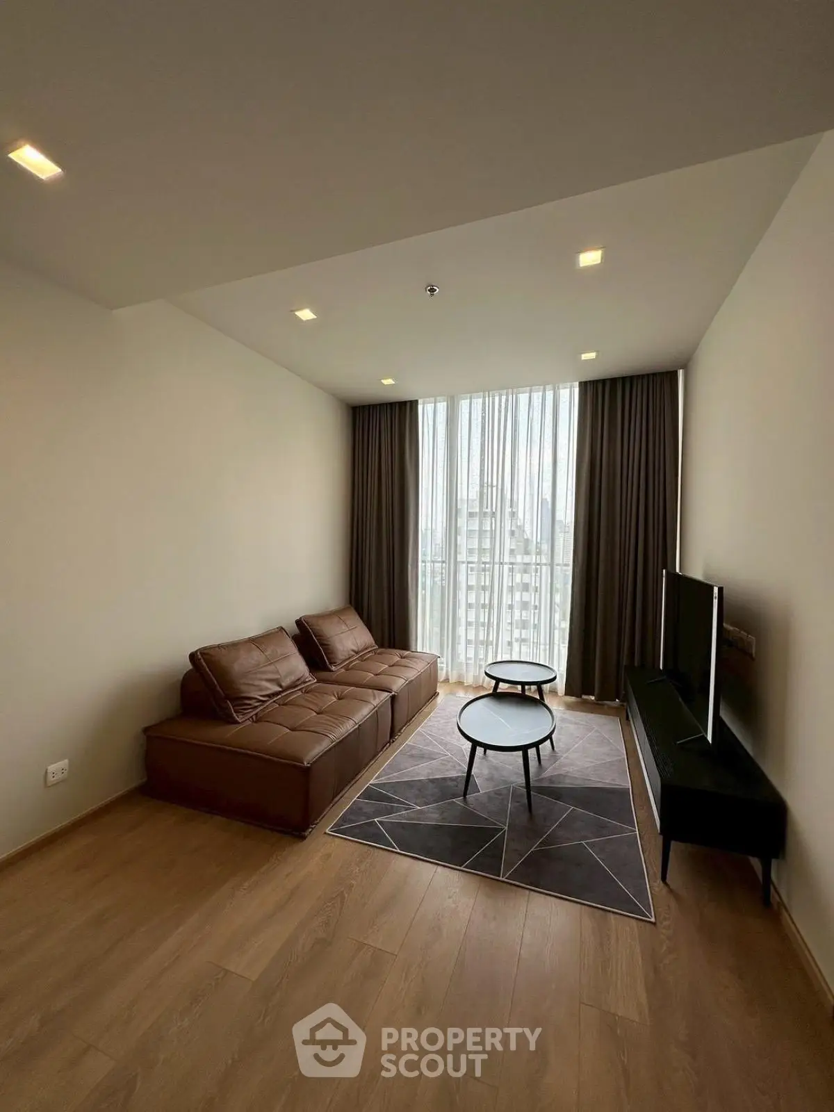 Modern living room with sleek furniture and large window offering natural light.