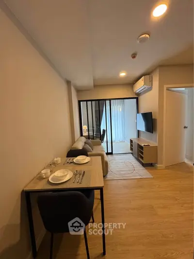 Modern living room with dining area and TV, featuring sleek furniture and warm lighting.