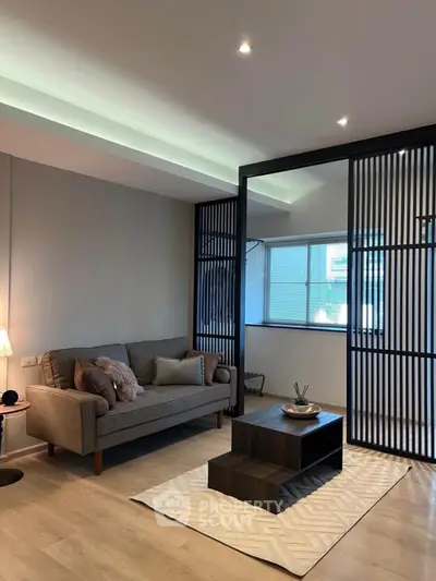 Modern living room with stylish decor and sliding partition, featuring cozy sofa and elegant coffee table.