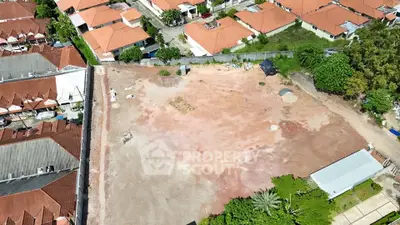 Aerial view of a vacant lot surrounded by residential houses with red roofs.