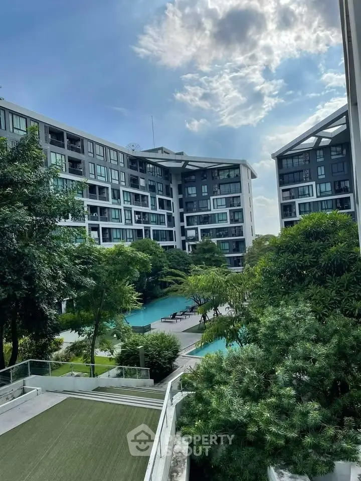 Luxurious condominium with pool and lush greenery, offering serene living environment.