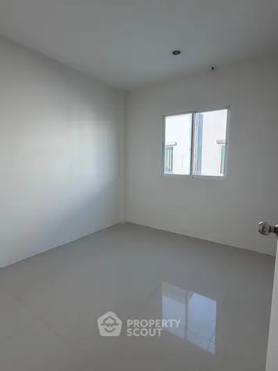 Spacious empty room with glossy tiled floor and bright window, perfect for customization.