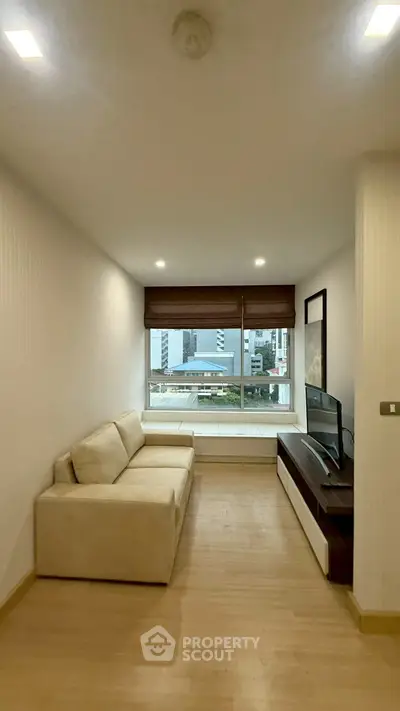 Cozy living room with city view, beige sofa, and modern TV setup