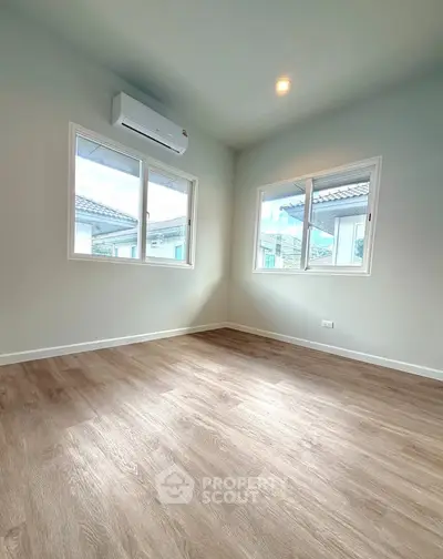 Spacious empty room with large windows and wooden flooring, perfect for customization.