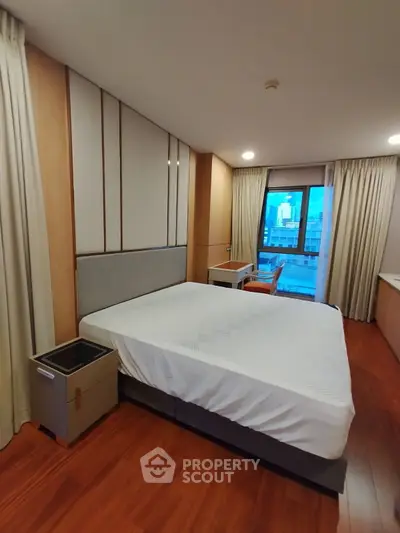 Spacious bedroom with city view and modern furnishings in luxury apartment
