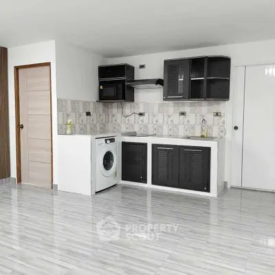 Modern kitchen with sleek black cabinets and washing machine in open layout.